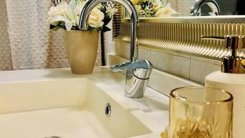 A bathroom with a sink, a mirror, and a potted plant.