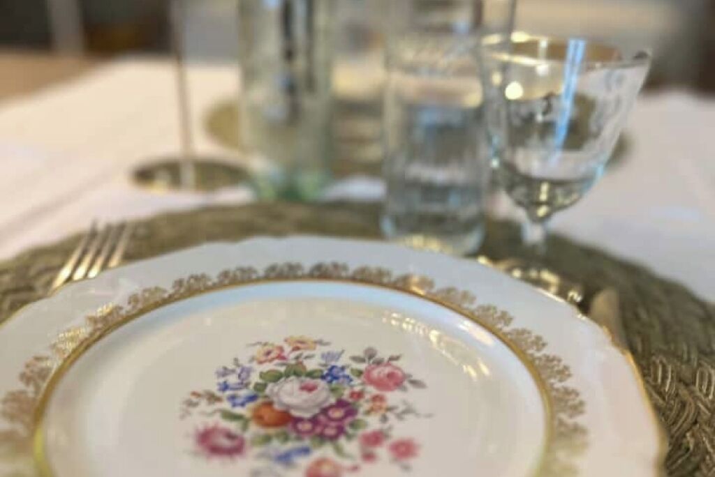 A table set with a floral-patterned plate, a glass of water, and a glass of wine.