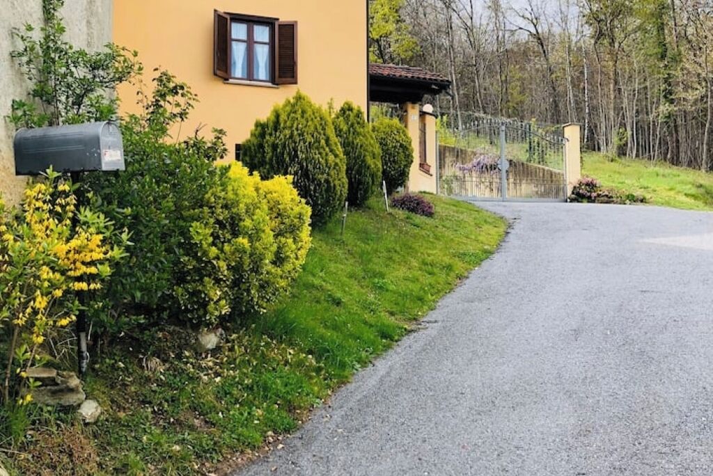 Un carrer residencial que condueix a una casa amb una closca de correu i una entrada tancada per una reixa.