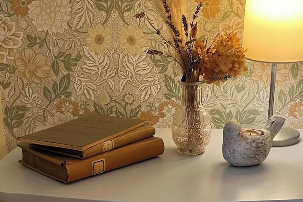 A table with a stack of books, a vase with dried flowers, and a candle holder.