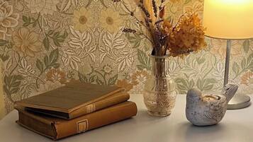 A table with a stack of books, a vase with dried flowers, and a candle holder.
