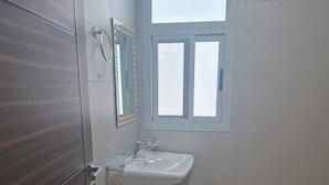 Un baño con lavamanos blanco, un espejo y una ventana.