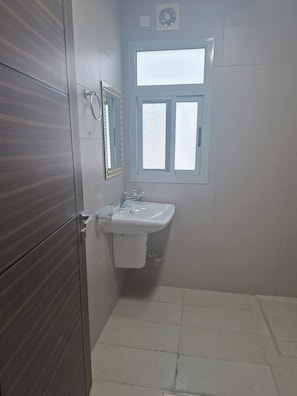 A bathroom with a white sink, a mirror, and a window. - Cozy studio in tranquil Seef with AC (Seef)