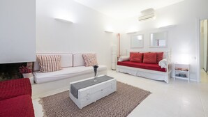 Una sala de estar moderna con un sofá blanco, un sofá rojo, una mesa de centro blanca y una alfombra estampada.