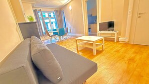 Een moderne woonkamer met een bank, een salontafel, een tv-meubel en een eethoek met stoelen.