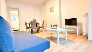 A living room with a sofa, a dining table with chairs, a TV on a stand, and a globe decoration.