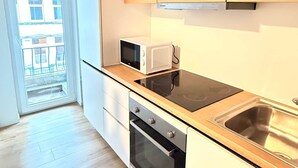A modern kitchen with wooden cabinets, a microwave, a stove, and a sink. - Orléans 41 (C) city center-train station-airport (Charleroi)