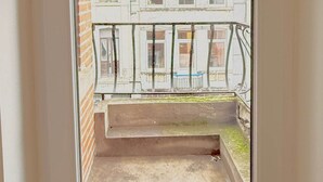 A narrow balcony with a metal railing, a view of adjacent buildings, and a concrete floor. - Orléans 41 (C) city center-train station-airport (Charleroi)