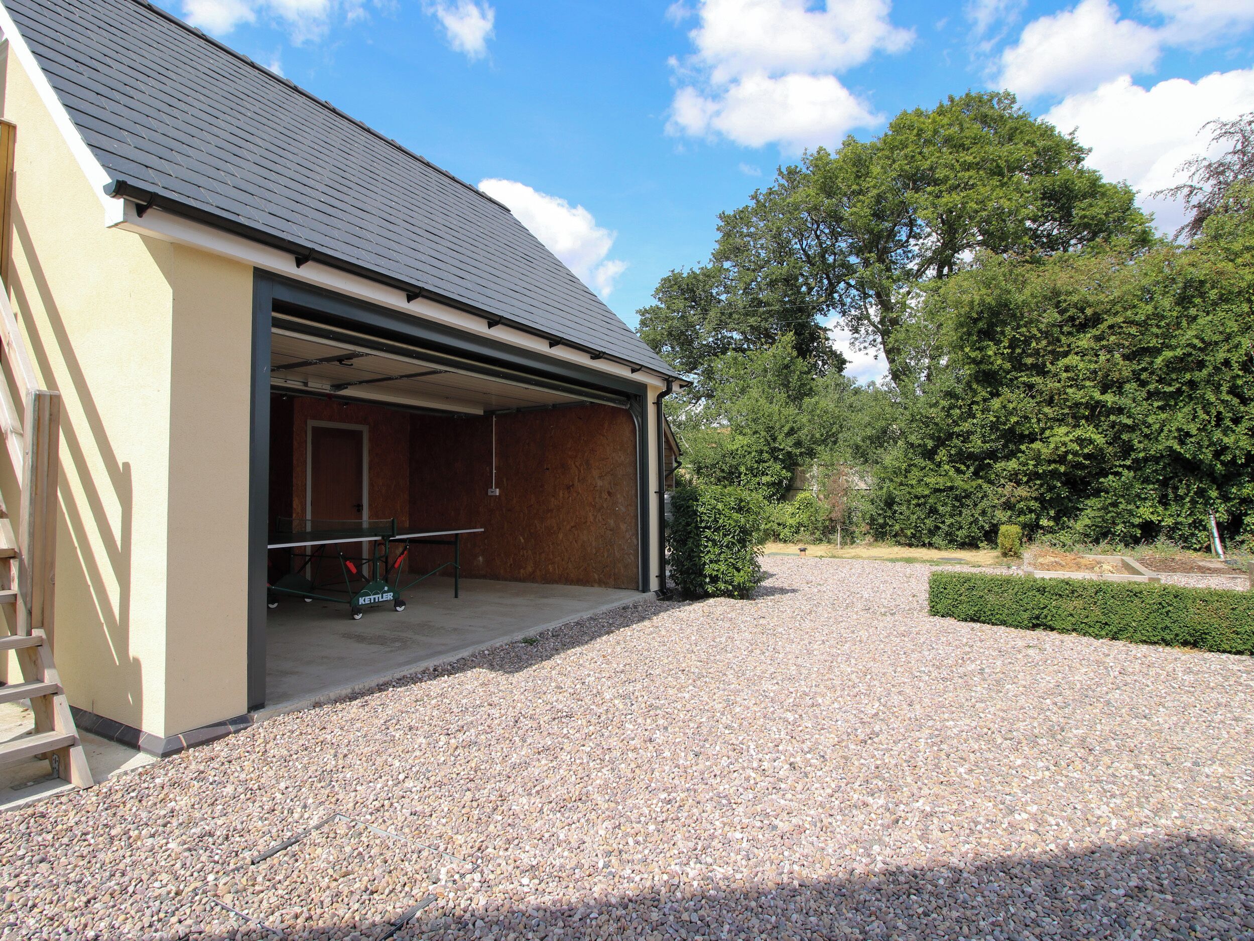 A building with an open garage and a gravel driveway.