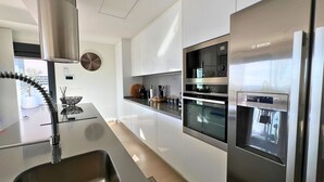 Una cocina moderna con campana extractora de acero inoxidable, horno empotrado y refrigerador Bosch.