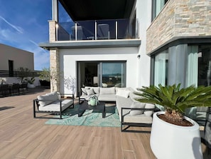 A modern outdoor living area with a sofa set, a dining table, and potted plants.