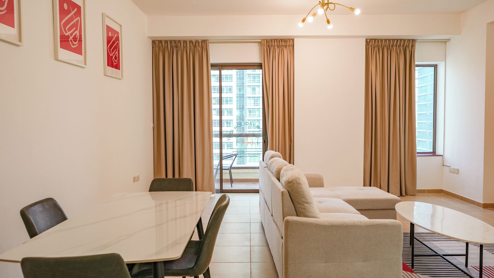 A modern room with a large table, two sofas, and a balcony with curtains.