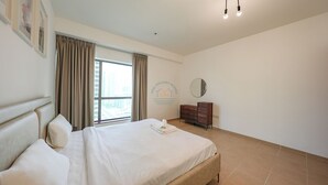 Een hotelkamer met een groot bed, een dressoir, een spiegel en een raam met gordijnen.