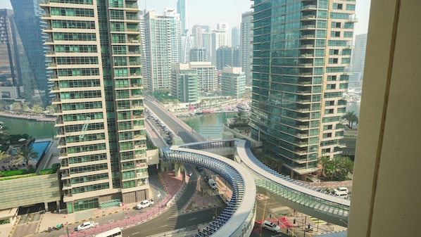A modern urban area with high-rise buildings, a curved pedestrian bridge, and a body of water.
