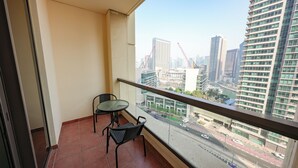 Een balkon met twee stoelen en een kleine tafel, met uitzicht op een stadsgezicht met hoge gebouwen en een rivier.