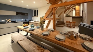 A modern kitchen with a dining area, wooden beams, and a staircase. - La Grange - at the Ancienne ferme (Steinseltz)