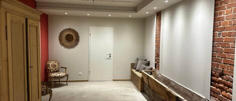 A hallway with a patterned rug, a wooden bench with cushions, a decorative mirror, and a door.