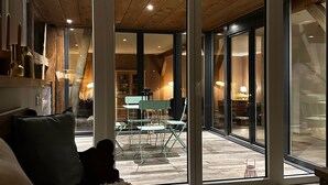 A modern living room with a large sliding glass door leading to an outdoor patio area. - L'Étable - at the Ancienne ferme (Steinseltz)