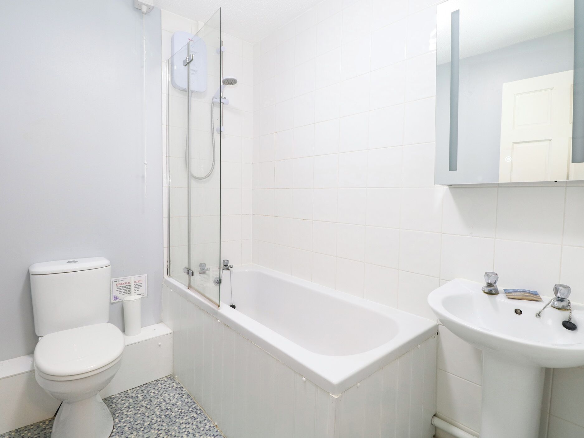 A bathroom with a toilet, a glass-enclosed shower, and a sink.