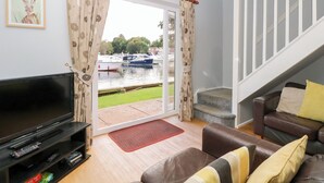 A living room with a TV, sofa, and a view of boats on water.