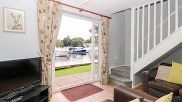 Ein Wohnzimmer mit Fernseher, Sofa und Blick auf Boote auf dem Wasser.