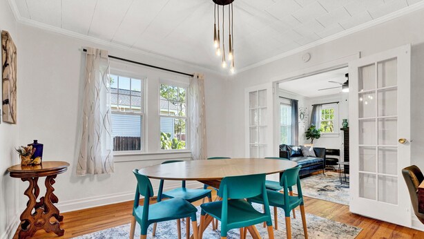 A dining area with a wooden table and teal chairs, a patterned rug, and a view of the outdoors through a window. - Pet Friendly Cute Cottage - Walk to PC/Downtown (Clinton)