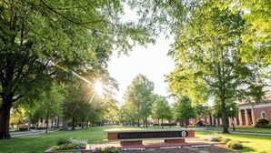 A well-maintained campus lawn with a prominent sign for Presbyterian College, surrounded by mature trees and a brick building in the background. - Pet Friendly Cute Cottage - Walk to PC/Downtown (Clinton)