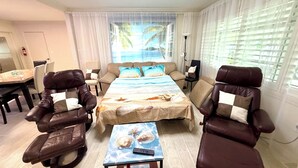 Una habitación de hotel con una cama, dos sillones de cuero, una mesa de comedor y un televisor.