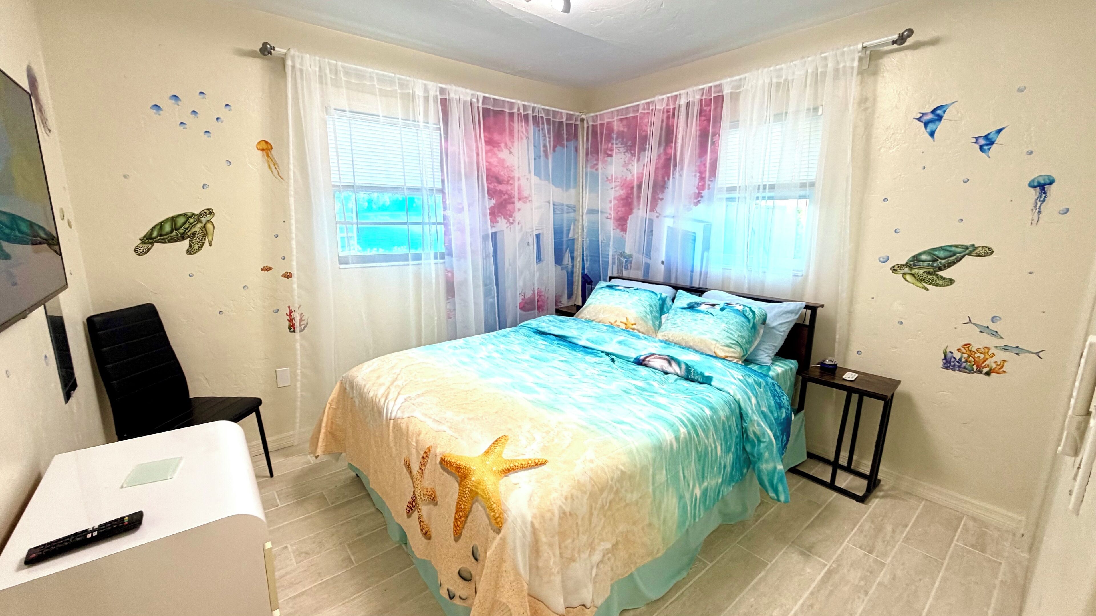 A bedroom with a bed, a desk, and a chair.
