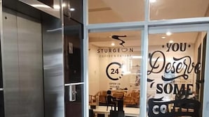 Interno di una caffetteria moderna con una porta vetrata che mostra il nome 'Sturgeon's Coffee & Eatery' e un cartello che indica servizio attivo 24 ore su 24.