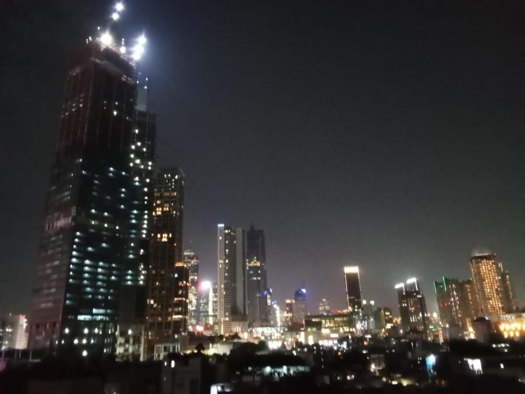 A nighttime cityscape with illuminated high-rise buildings.