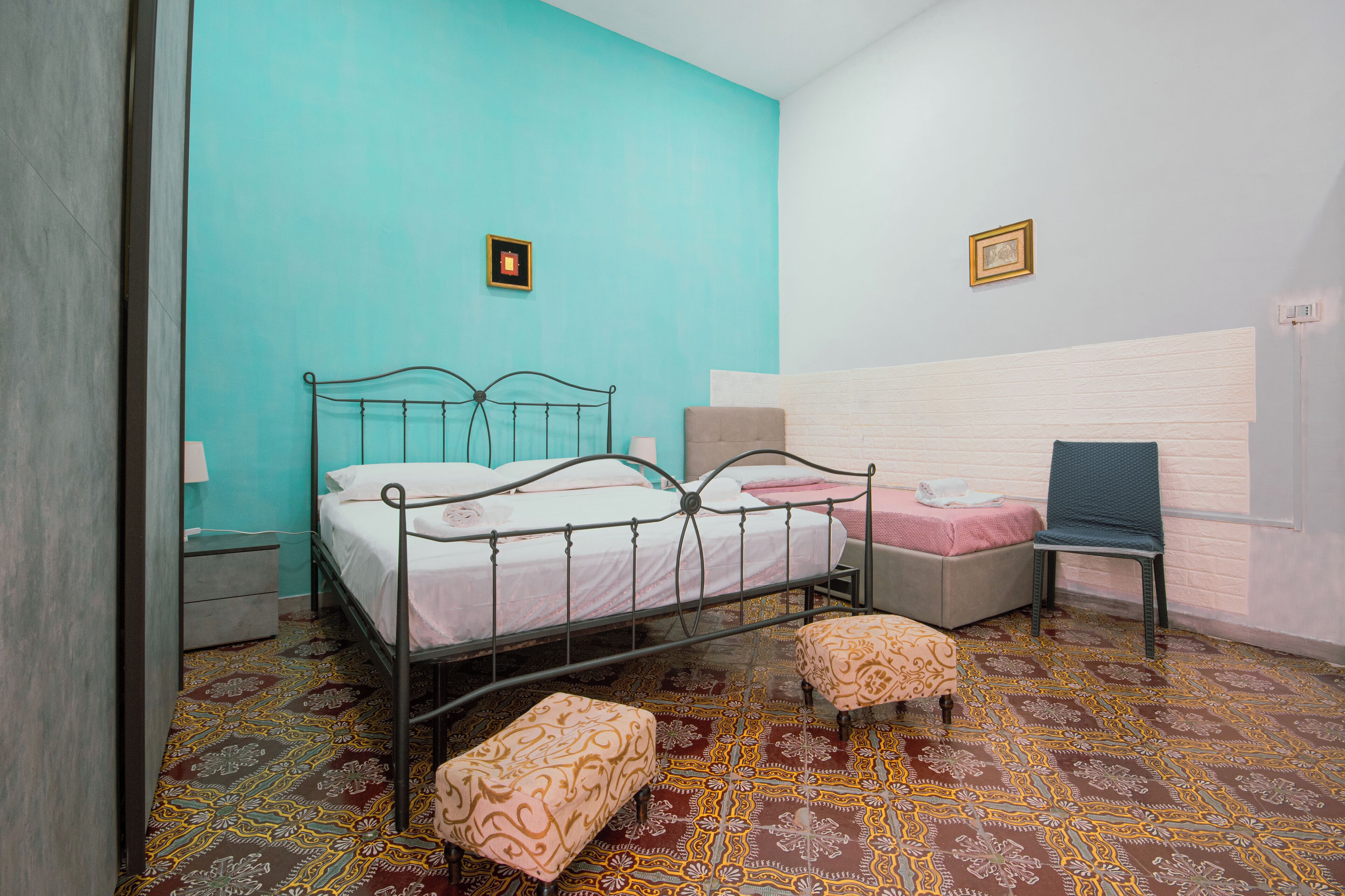 Een slaapkamer met een bed, twee nachtkastjes, een stoel, een bankje en een kamer met een patroon.