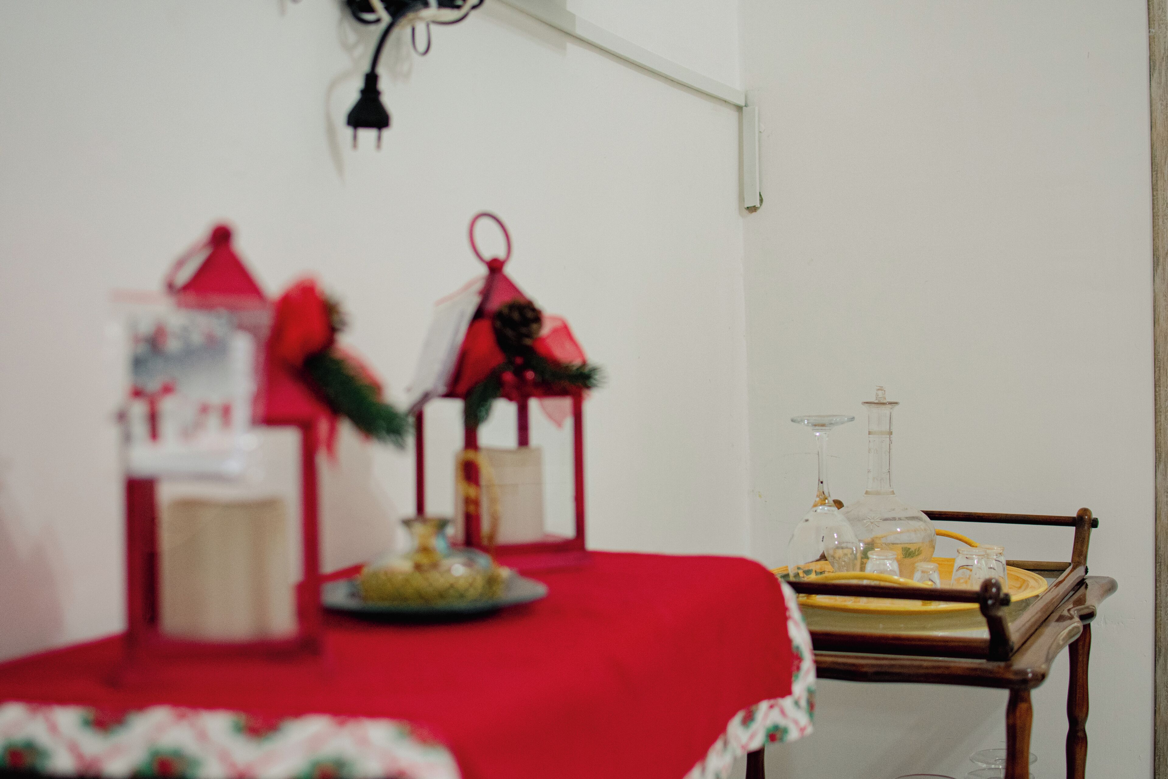 A table with a red tablecloth, two red lanterns, and a tray with glassware.