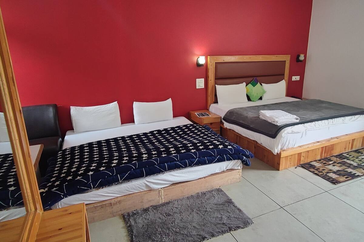 Una cama doble con estructura de madera, una mesita de noche y una pared roja.