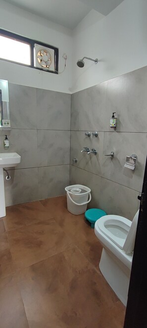 A bathroom with a sink, toilet, shower, and a fan mounted on the wall. - Woodward 2 by 4wildflower (Bhuntar)