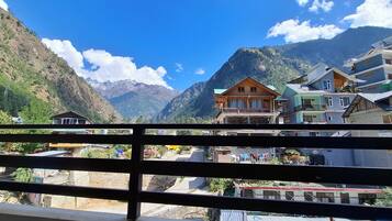 A mountain village with traditional wooden houses, a clear sky, and a valley.