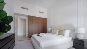 A modern bedroom with a large bed, a wardrobe, a bedside table, and a plant. - G14 Jadeel 3 in Dubai (Dubai)