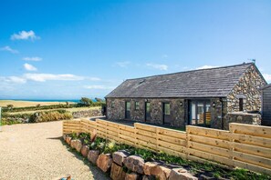 A stone building with a gravel driveway and wooden fence. - Crowrach - sleeps 7 guests  in 3 bedrooms (Abersoch)