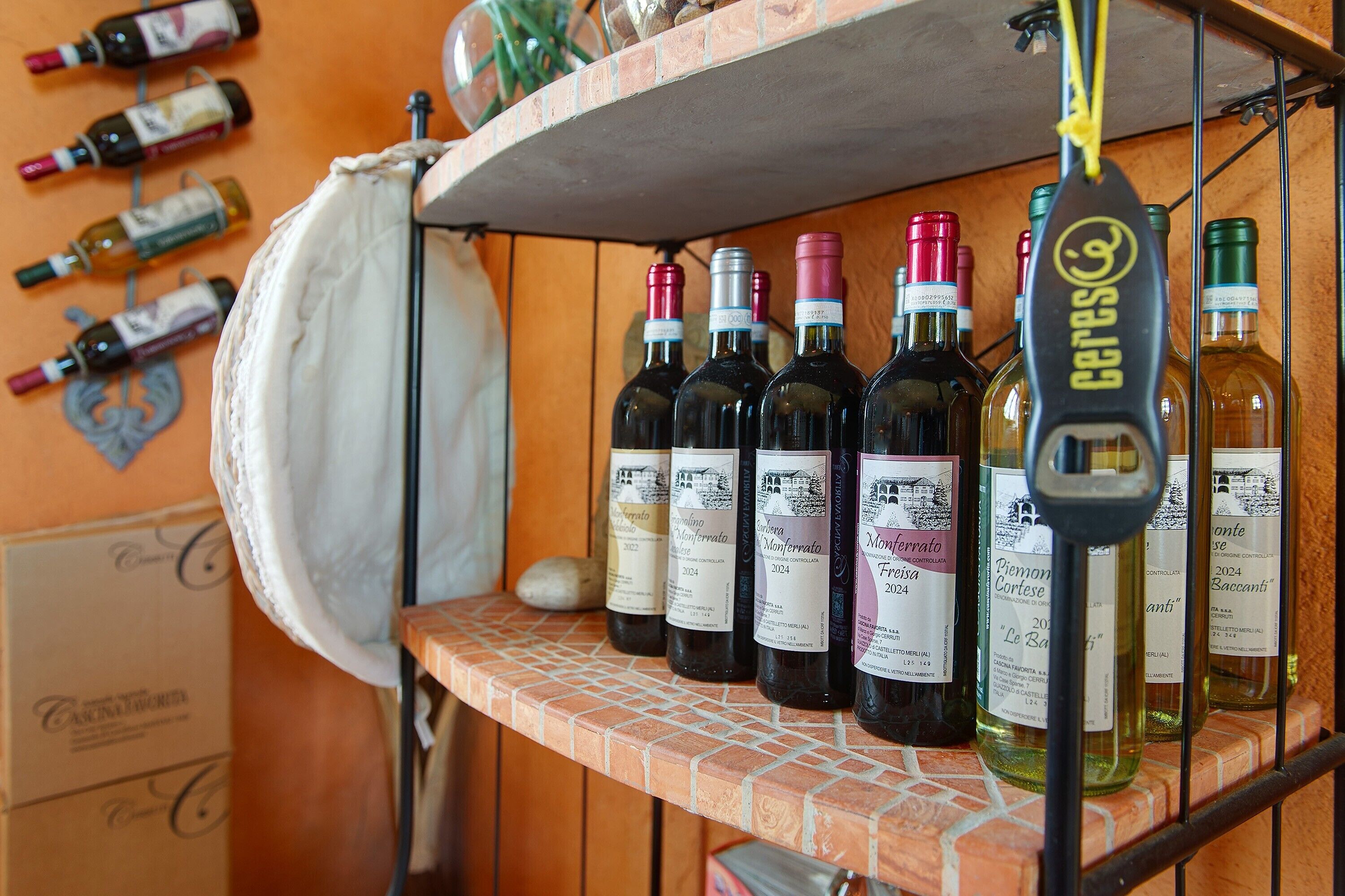 Un étagère à vin contenant des bouteilles étiquetées « Monterato Fresia 2024 » et « Piemont Cortese 2024 », le tout adossé à un mur de briques.