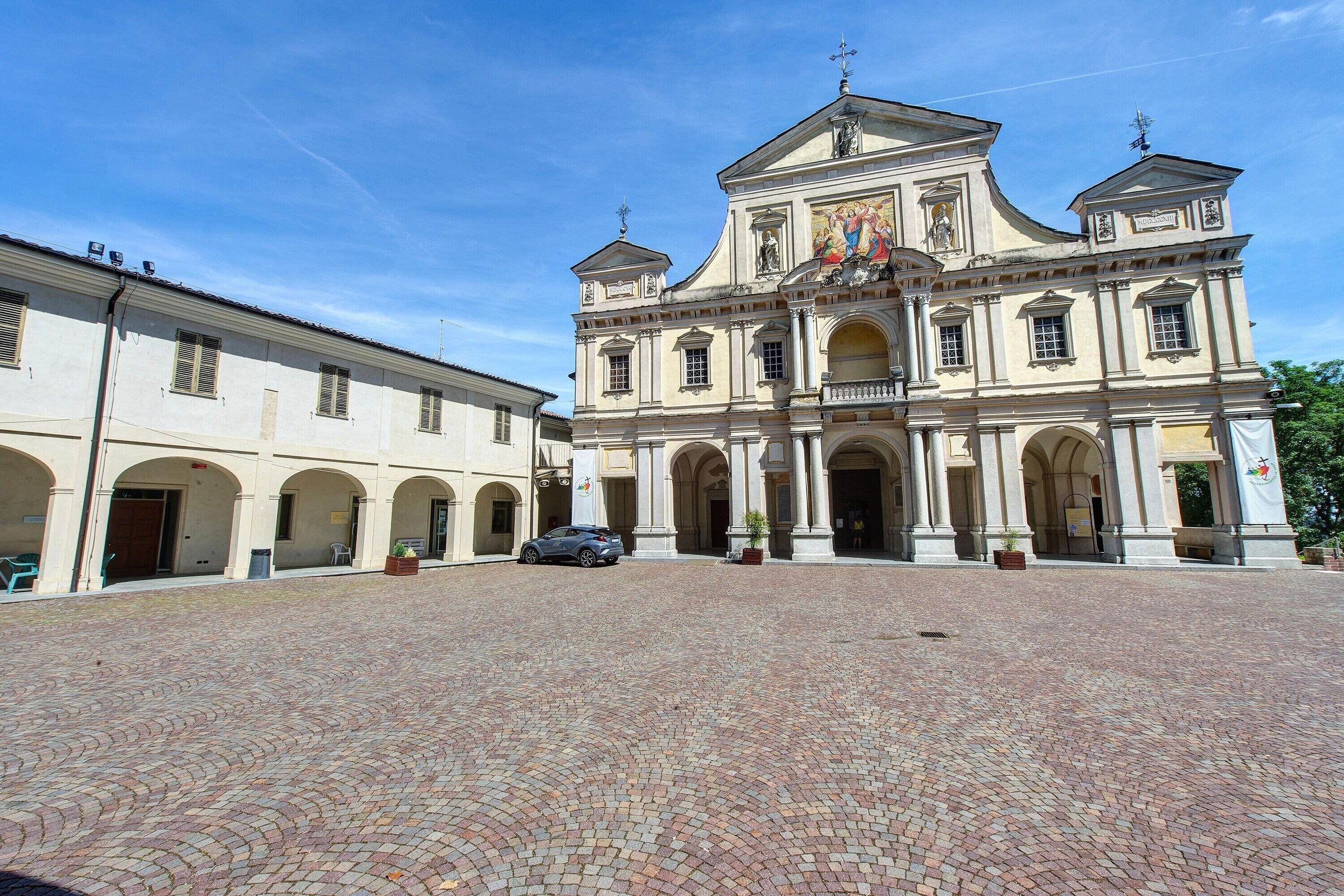 A historic building with a courtyard, arched doorways, and a paved ground.