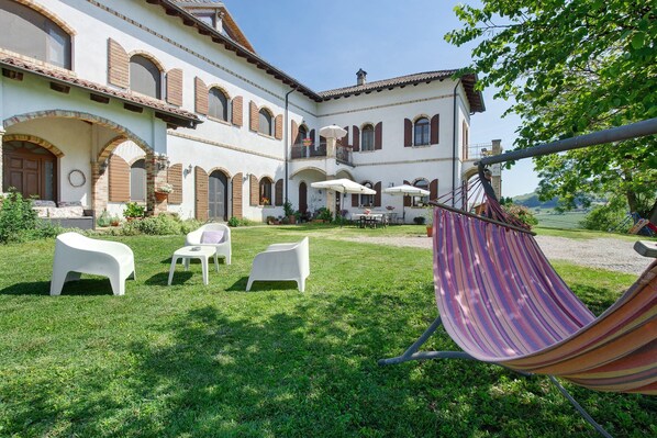 A courtyard with outdoor seating, a hammock, and a building with arched windows and balconies.