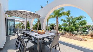 An outdoor dining area with a table, chairs, and a large umbrella. - Ayia Napa Panorama Villa (Ayia Napa)
