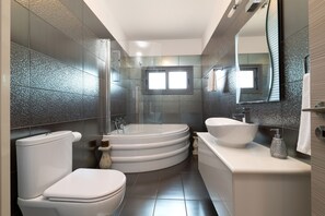 A modern bathroom with a toilet, bidet, bathtub, and sink.