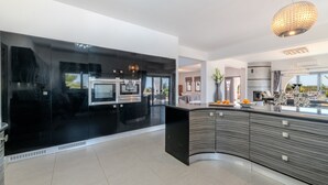 A modern kitchen with a curved island, black cabinetry, and a large window. - Ayia Napa Panorama Villa (Ayia Napa)