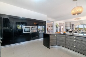 A modern kitchen with a curved island, black cabinetry, and a large window.