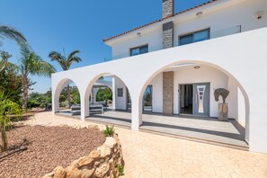 Un bâtiment moderne aux murs blancs, aux entrées en arc de cercle et à la façade en pierre.