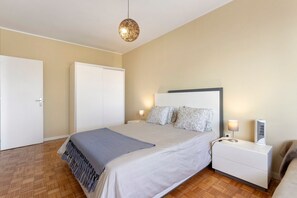 A bedroom with a bed, bedside table, lamp, and wardrobe.