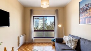 A living room with a sofa, a TV, a window with curtains, a lamp, and a painting on the wall. - Apartment 'Destiny Oporto' with Wi-Fi (Maia)