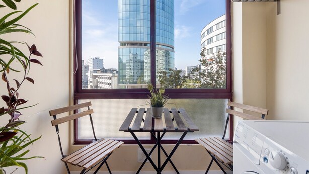 A balcony with a view of modern buildings, a wooden table with chairs, and a potted plant. - Apartment 'Destiny Oporto' with Wi-Fi (Maia)