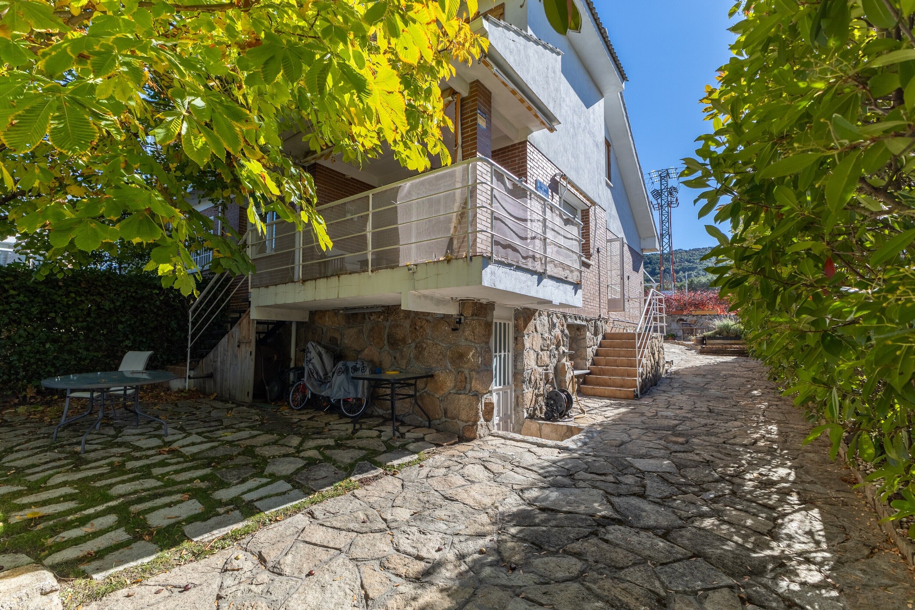 Un patio empedrado con un edificio de dos pisos, mobiliario exterior y una bicicleta.